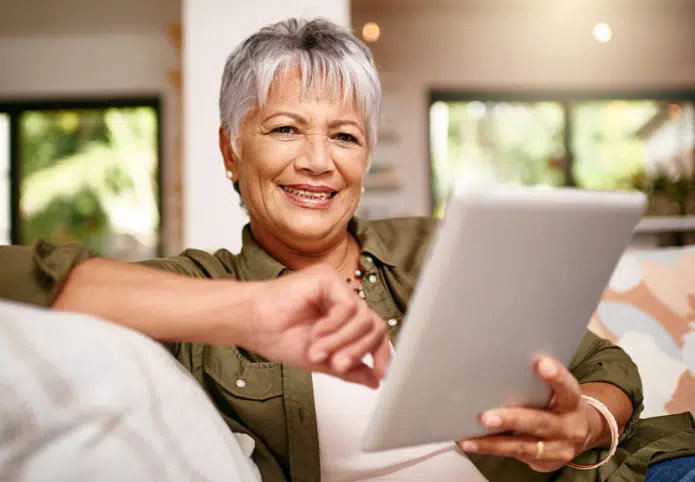 now ive got more time stream my favorite movies portrait happy older woman relaxing sofa with her digital tablet home 2